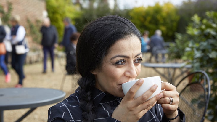 A woman sitting outside a cafe in October at Ham House and Garden, Surrey